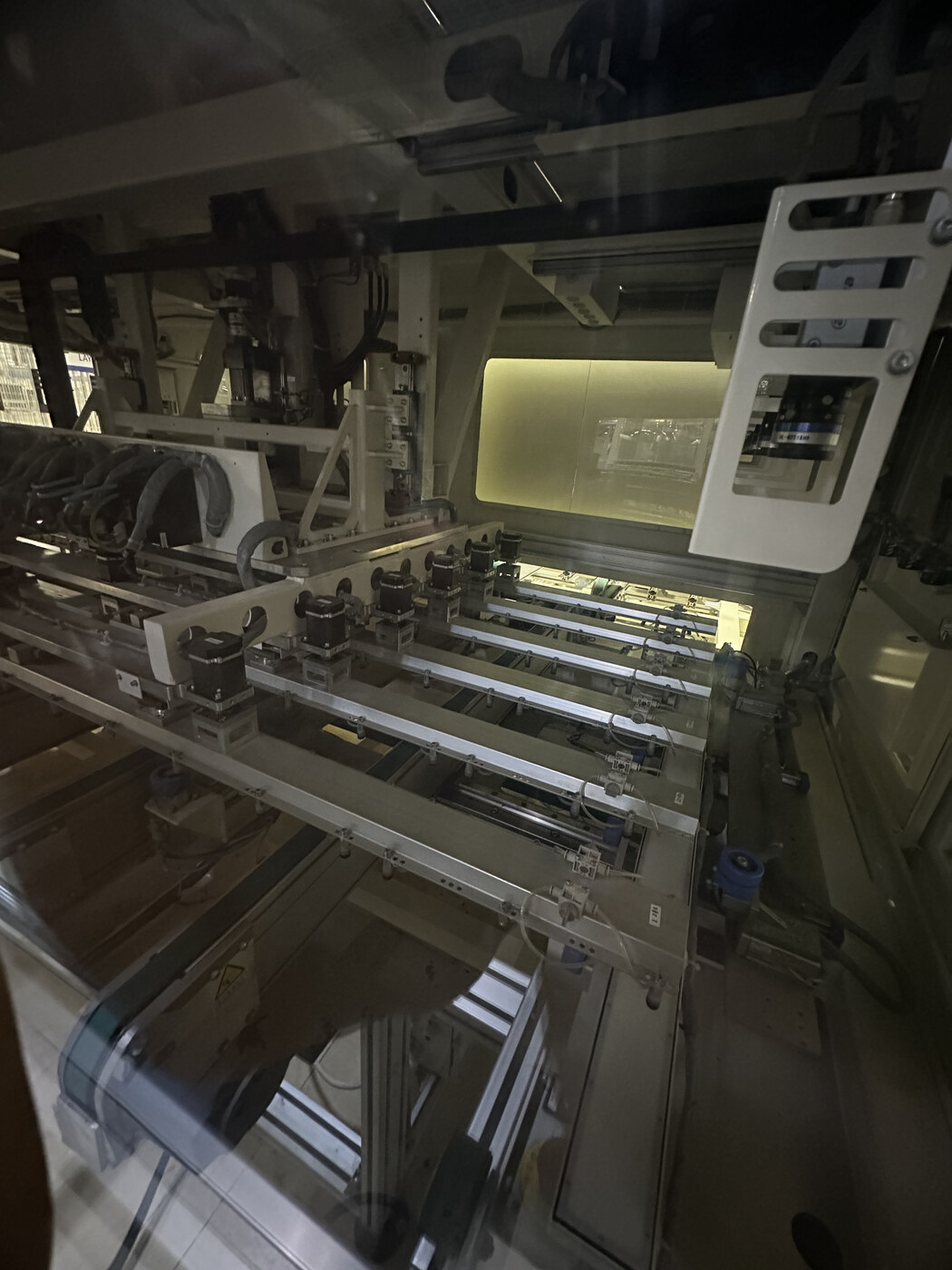 Interior view of automated solar manufacturing equipment behind a protective enclosure